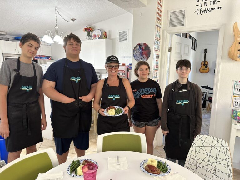 Students in black aprons pose together in the kitchen