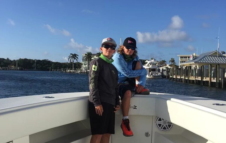 Two students ride on the bow of a boat