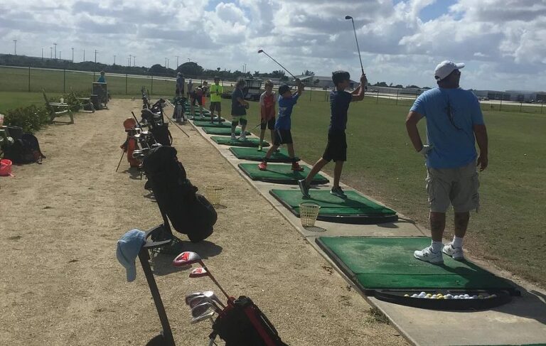 Students hit golf balls in a row at a driving range